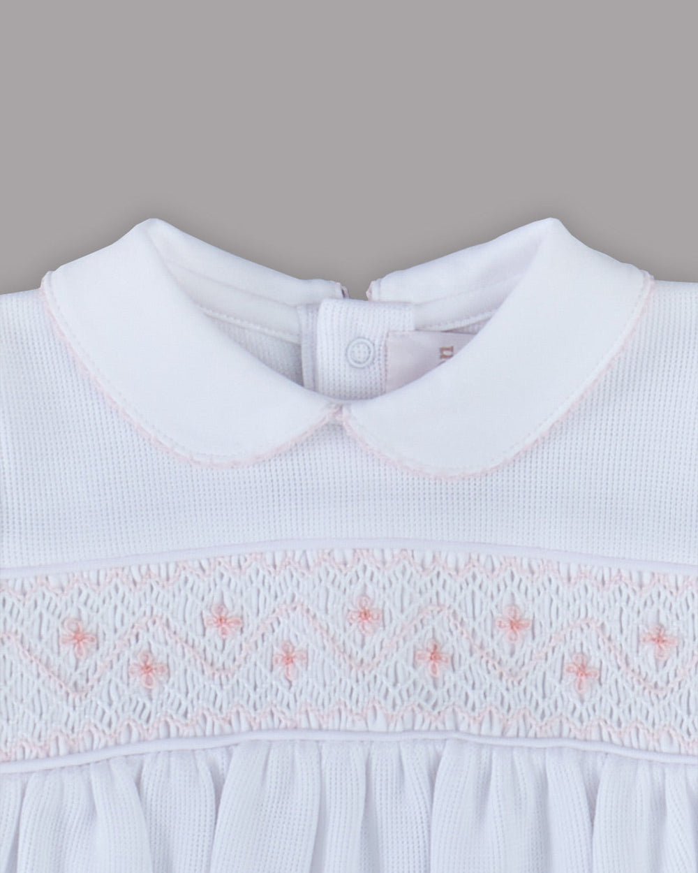 Romper branco para bebê com bordados rosas, desenho delicado e encantador para qualquer ocasião especial.