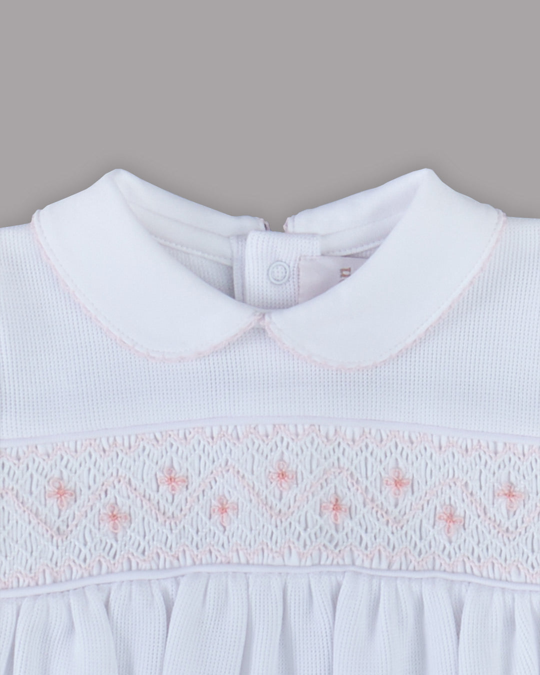 Romper branco para bebê com bordados rosas, desenho delicado e encantador para qualquer ocasião especial.