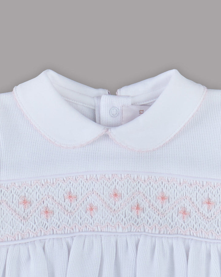 Romper branco para bebê com bordados rosas, desenho delicado e encantador para qualquer ocasião especial.